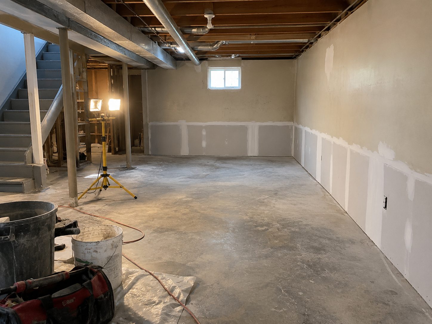A basement with new drywall hung to the flood cut line, taped and ready for texture.